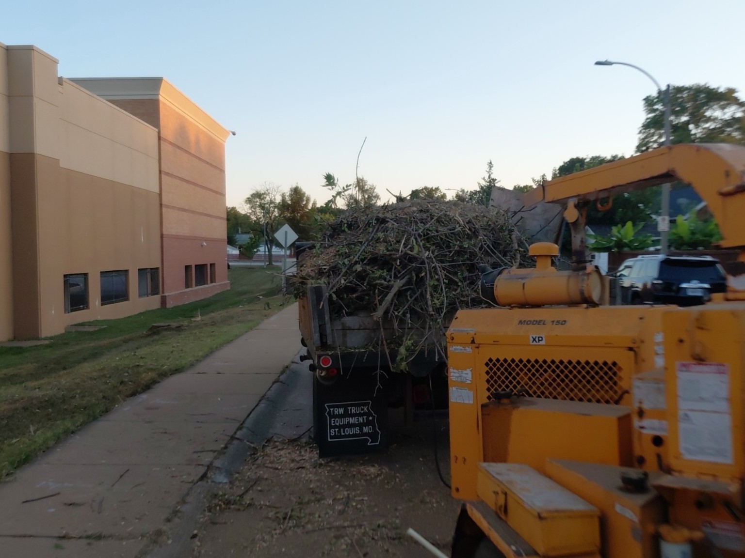 Chipper and truck handling brush beside the commercial property